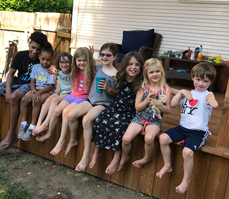 Eight Concordia Kids News kids sitting on a ledge