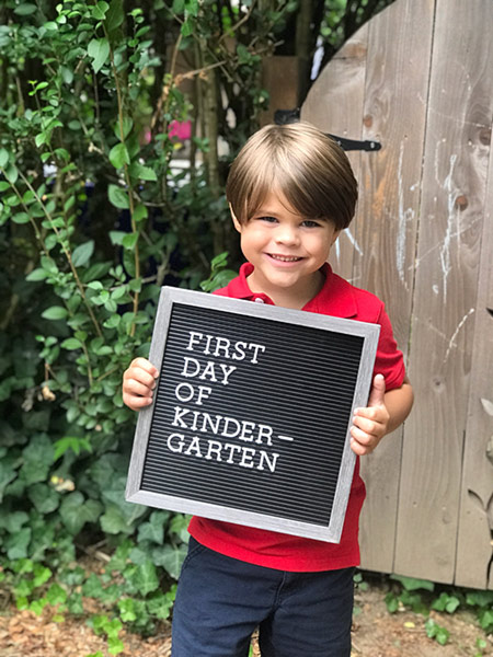 boy holding sign for first day of kindergarten